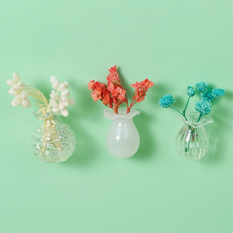 Three small vases with dried flowers on a light green background