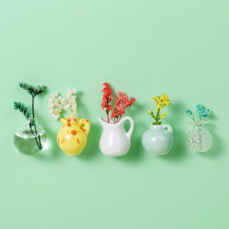 Set of colorful mini vases with plants on a light green background