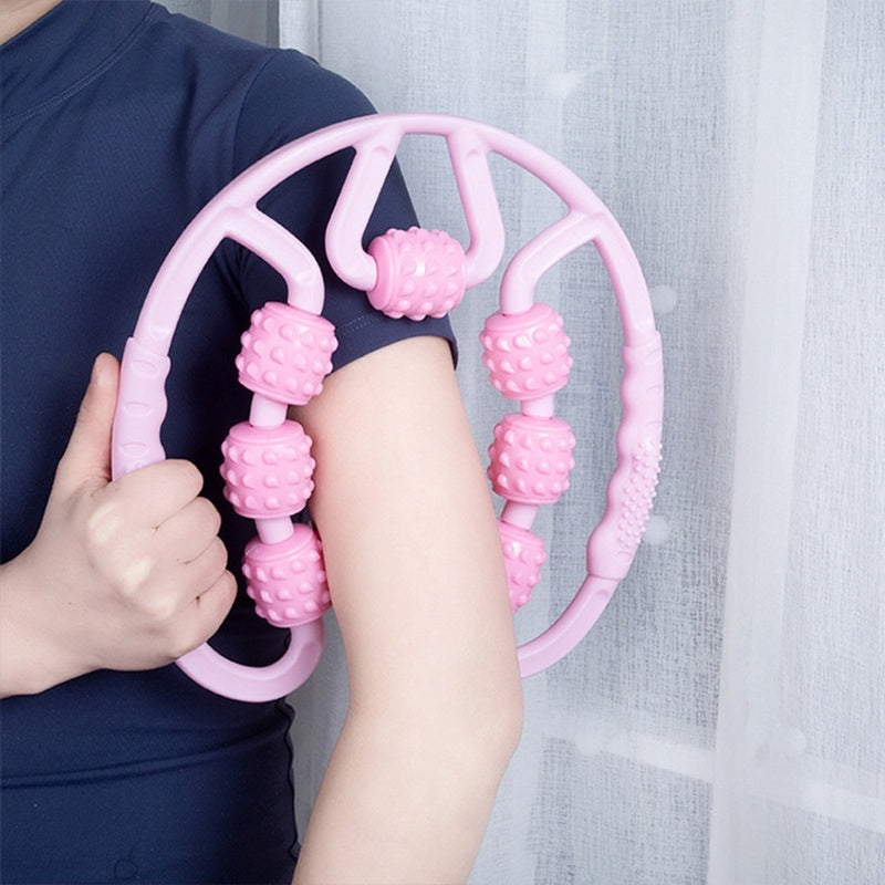 Person using a pink massage wheel on their arm against a light curtain background