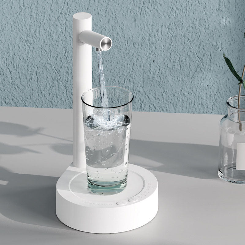 White electric water faucet dispensing water into a glass on a light gray surface with a light blue wall background.