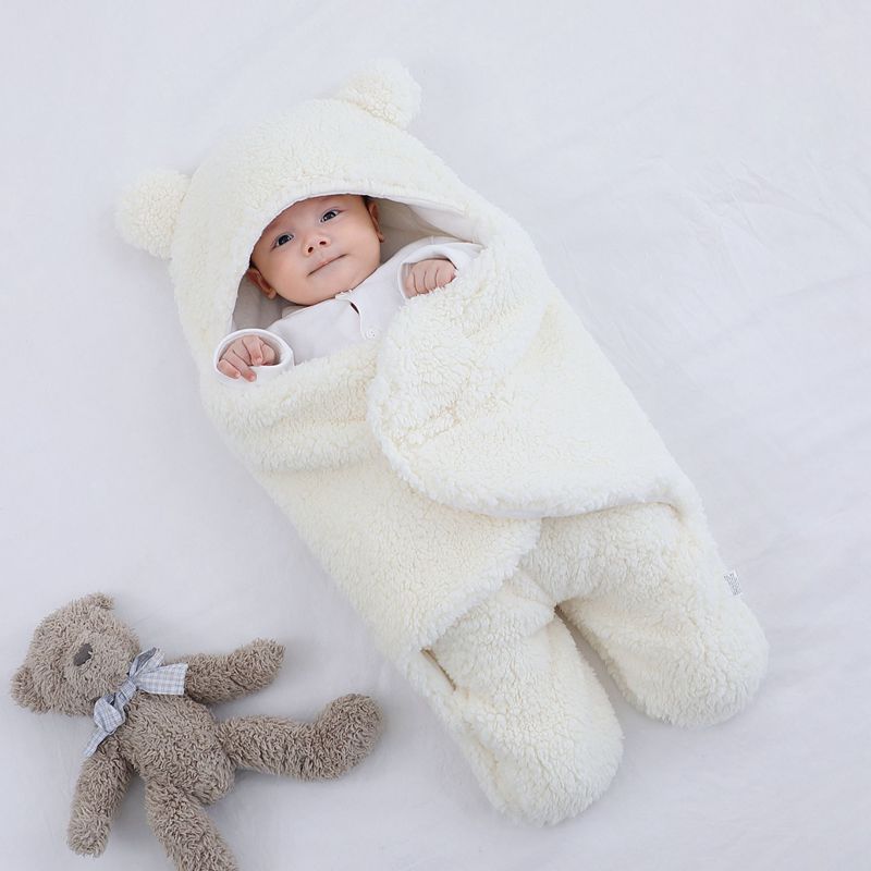 Baby in a white fluffy outfit with a teddy bear on a light gray background