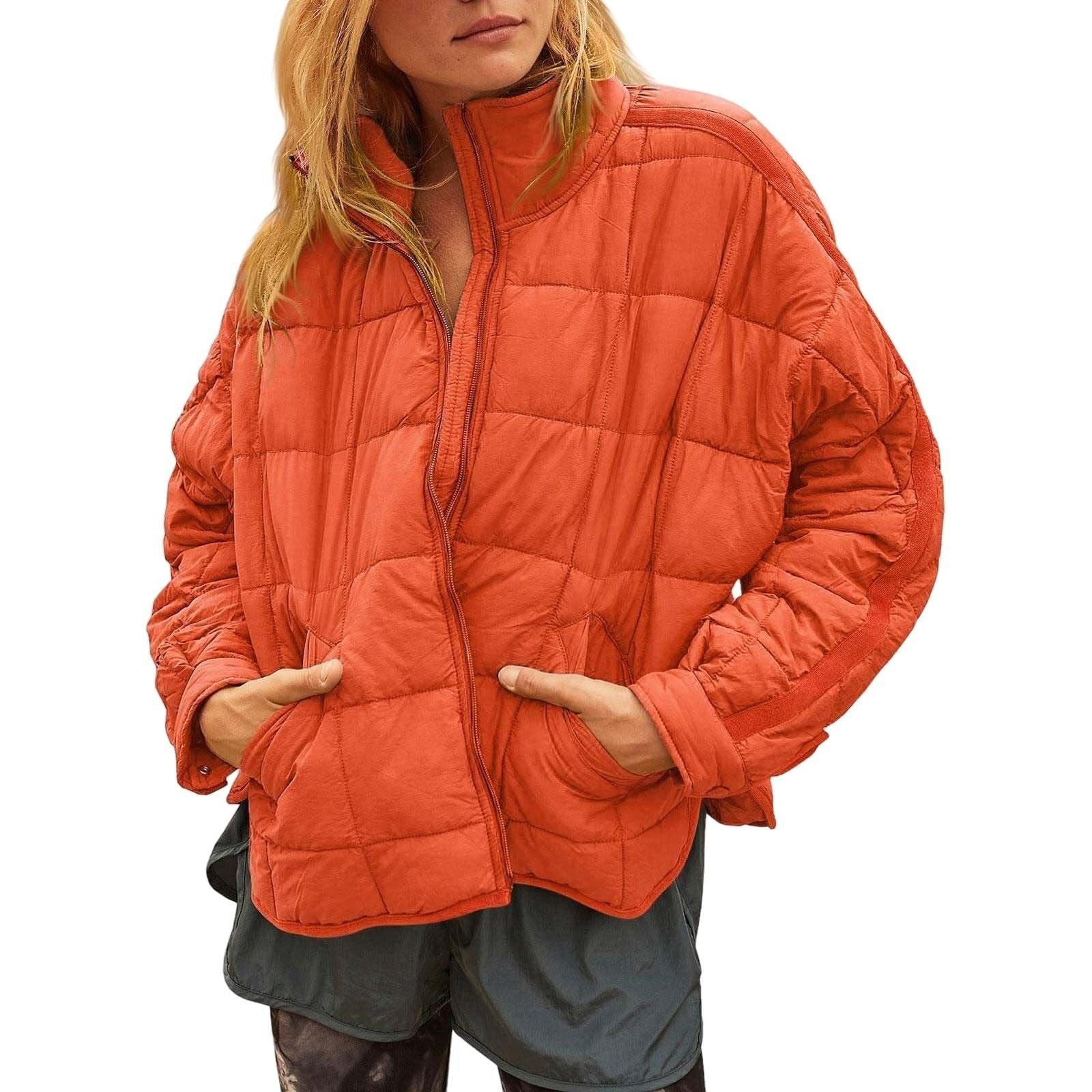 Person wearing an orange quilted jacket on a white background