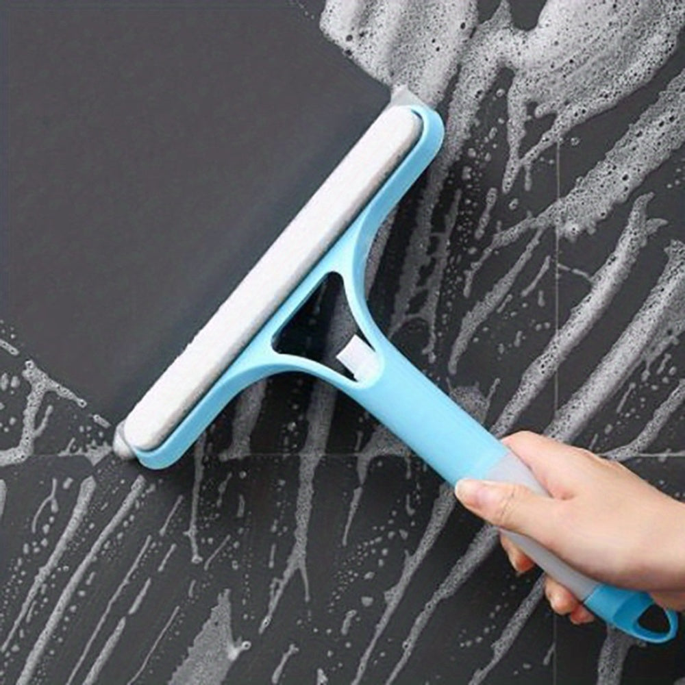 Cleaning tool with a blue handle and white squeegee blade being used on a soapy surface.