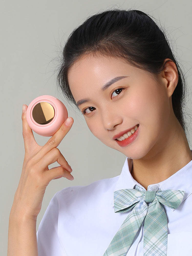 Woman holding a pink compact mirror against a plain background