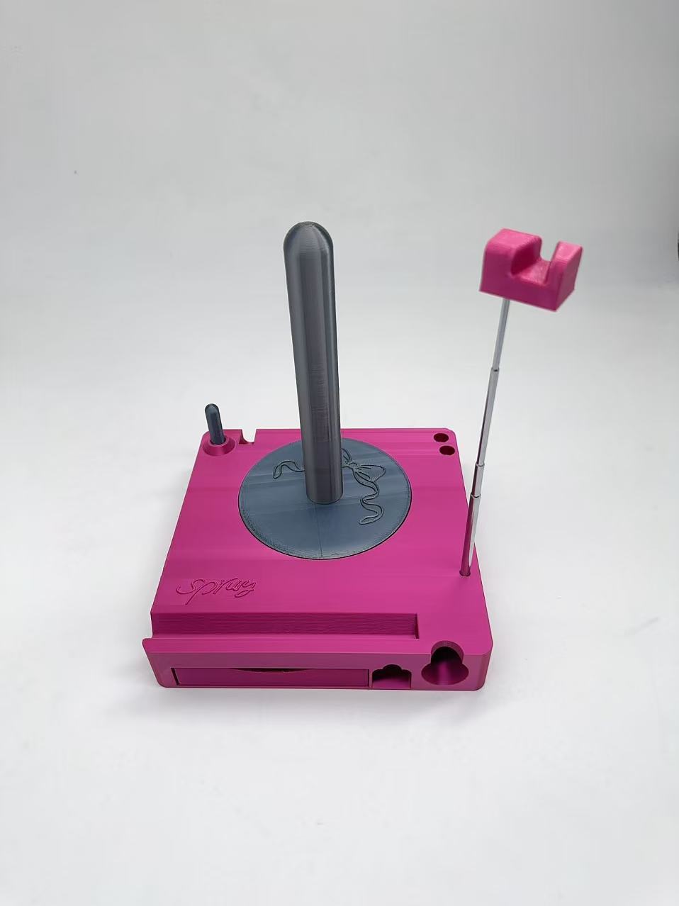 Pink mechanical device with a black rod and pink component on a white background