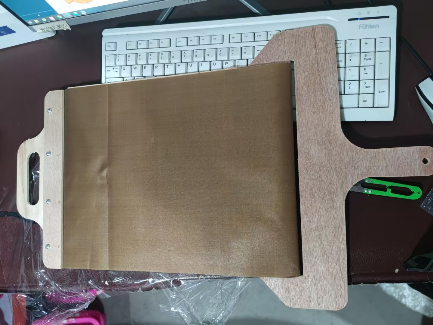 Brown leather wallet on a desk with a keyboard and computer monitor in the background