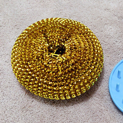 Gold scrubber on a gray surface with a blue object partially visible
