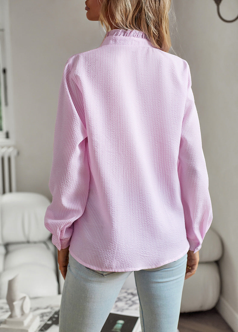 Person wearing a light pink textured blouse in an indoor setting
