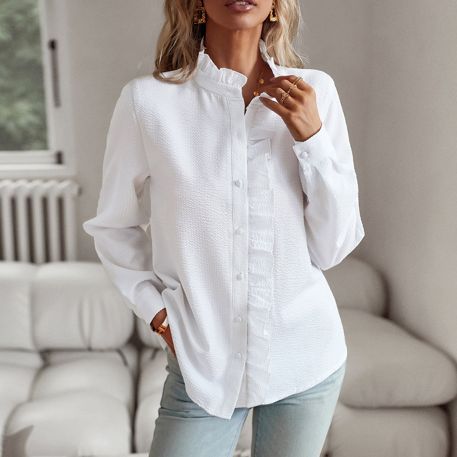Woman wearing a white button-up shirt and light blue jeans in a living room setting.