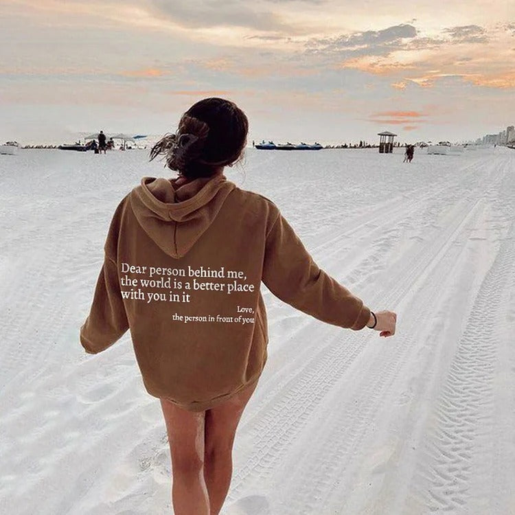 Person wearing a hoodie with a message in a snowy landscape