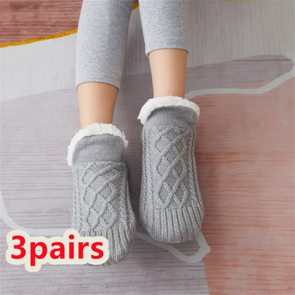 Gray cable knit socks with white fleece lining worn by a person on a wooden floor.