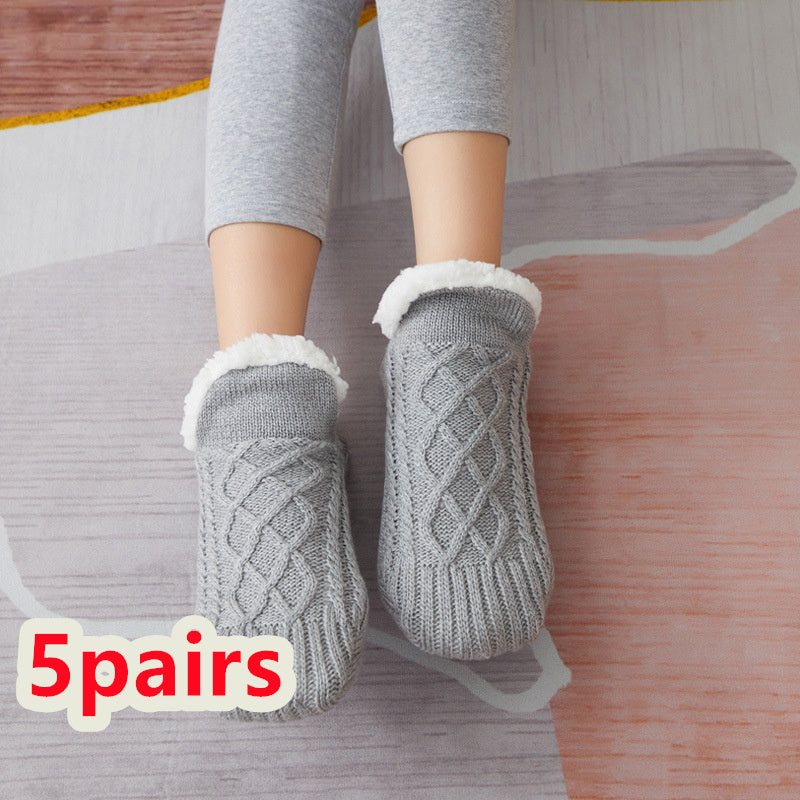 Gray cable knit socks with white fleece lining worn by a person on a wooden floor.
