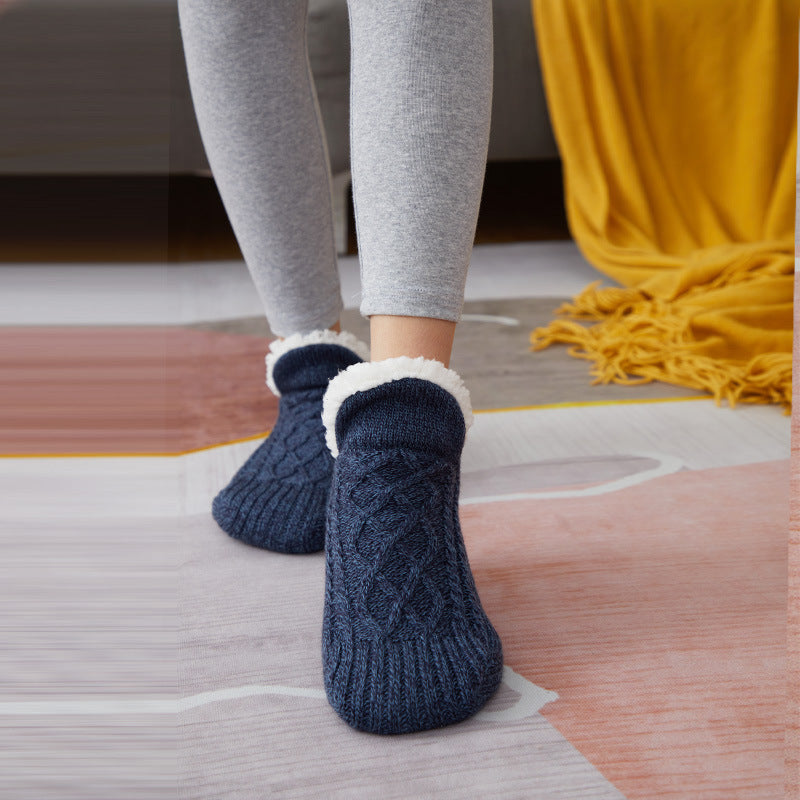 Person wearing blue cable knit socks with white cuffs on a wooden floor.