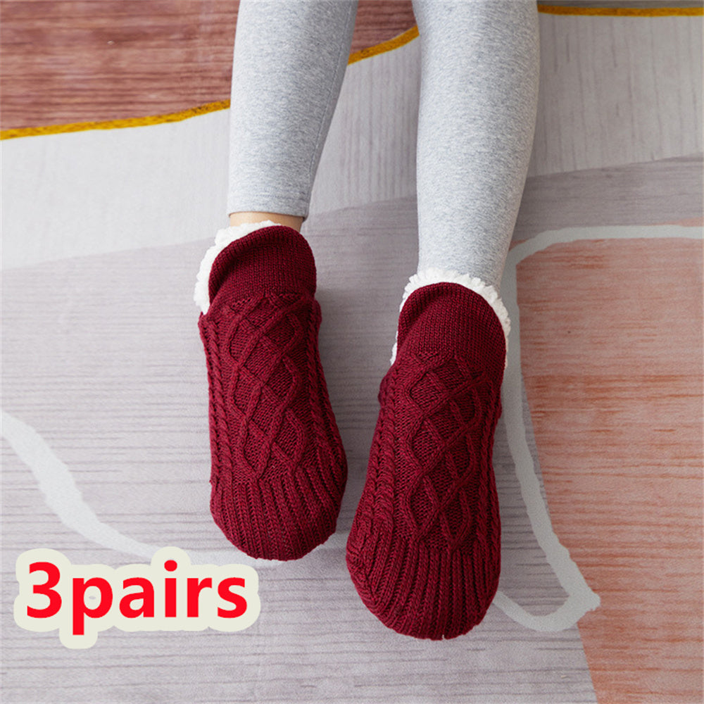 Red textured socks worn with gray leggings on a light wooden floor.