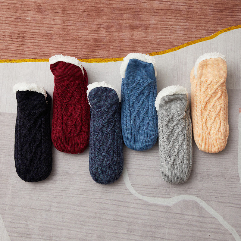 Set of six knitted socks in black, red, blue, gray, and beige on a wooden surface.