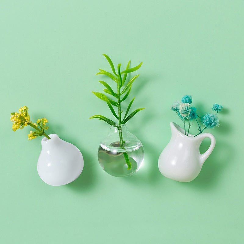Three small vases with plants on a light green background